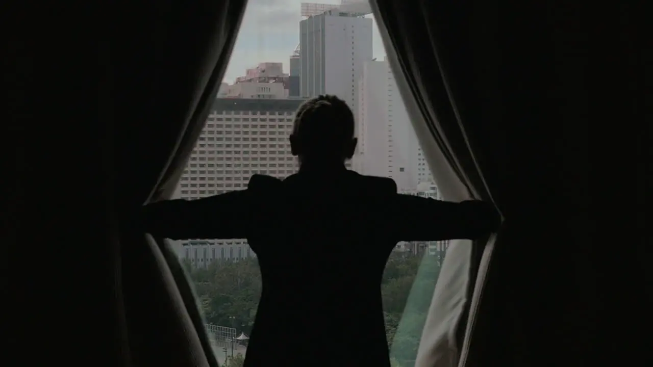 Woman opening curtains and looking at Hong Kong