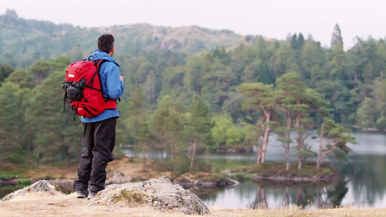 Caucasian adult man on the left shot standing on a hill admiring the view of a lake back view Lake District UK