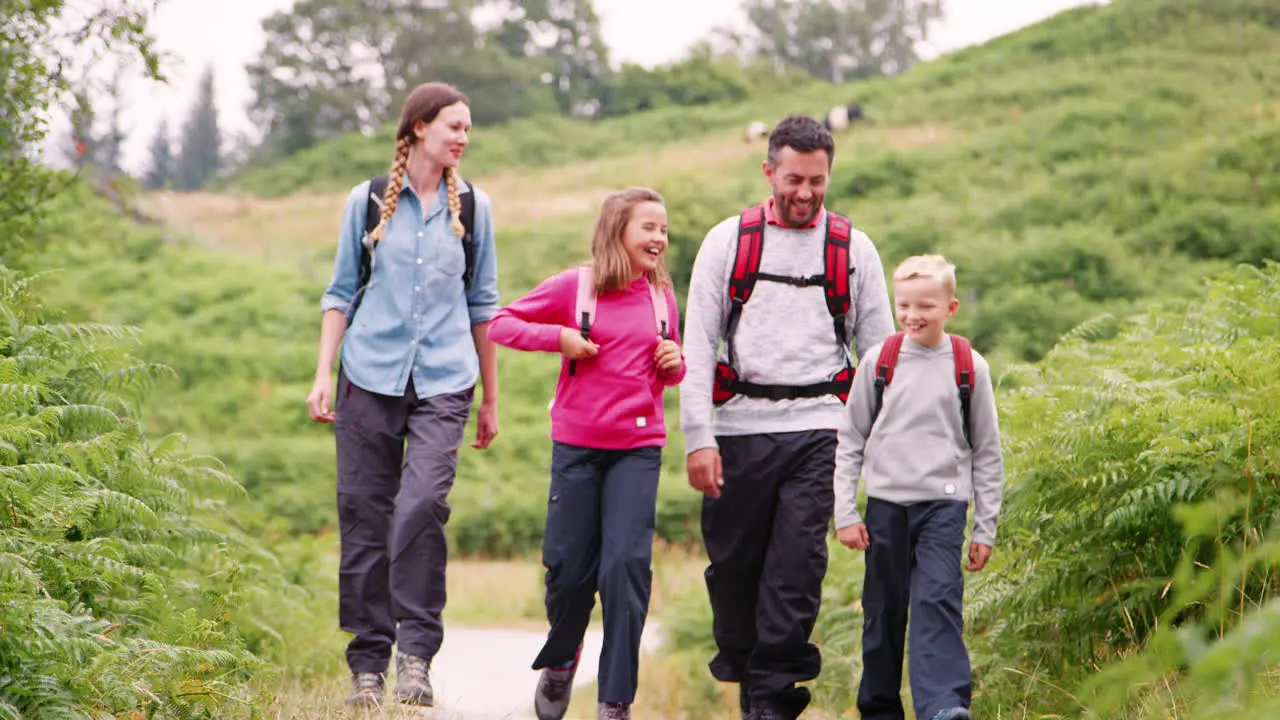 Parents and children walking on a countryside path during a family camping holiday Lake District UK