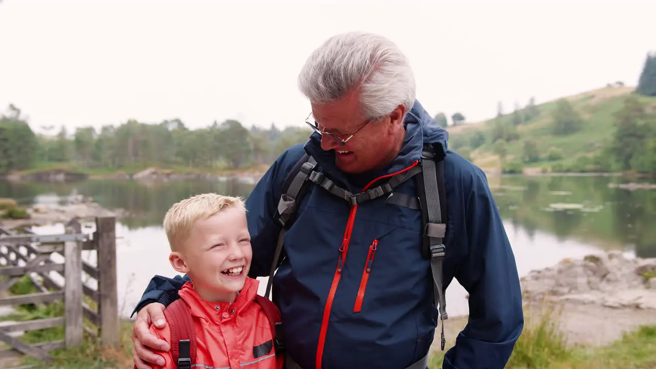 Grandfather and grandson laughing standing at the shore of a lake close up Lake District UK