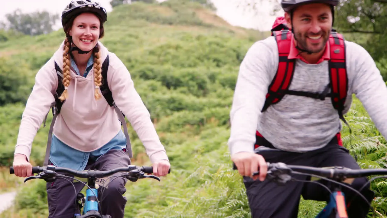 Young adult couple riding mountain bikes in the countryside during a camping holiday Lake District UK