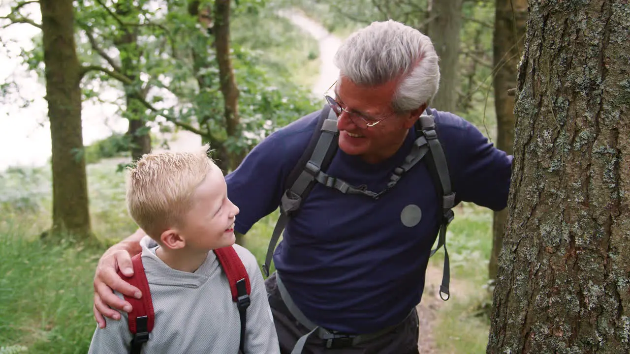 Grandfather and grandson taking a break while hiking in a forest Lake District UK