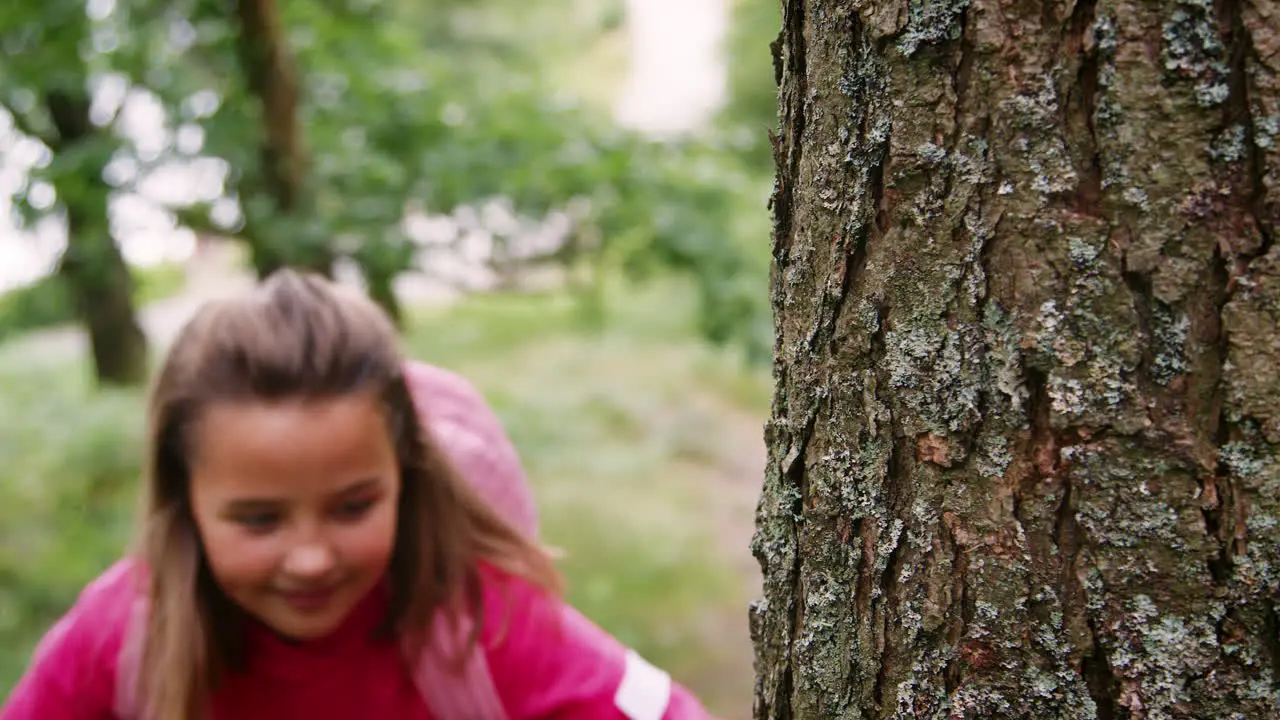 A girl walks into focus hiking between trees in a forest close up Lake District UK