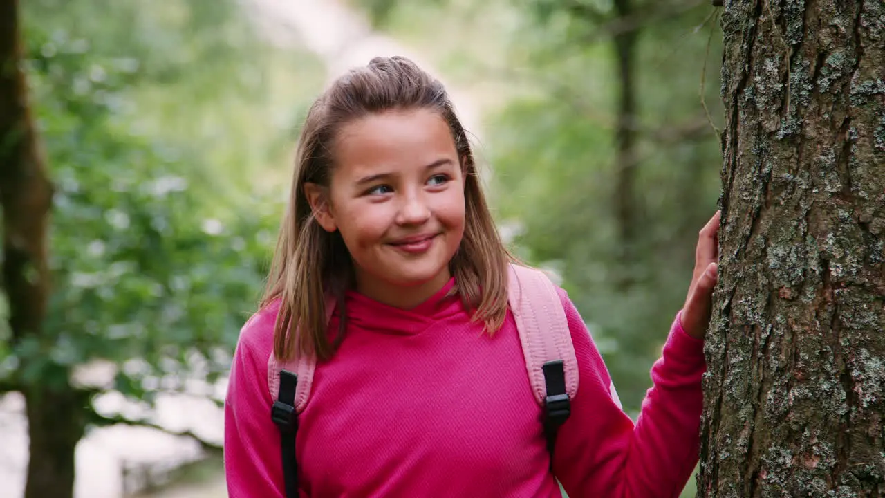 A girl standing between trees in a forest looking around close up Lake District UK