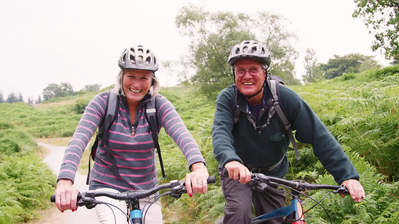 Senior couple sitting on mountain bikes in the countryside during a camping holiday Lake District UK