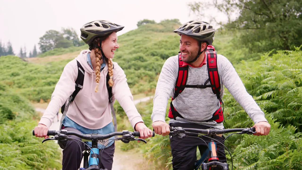 Young adult couple sitting on mountain bikes close up Lake District UK