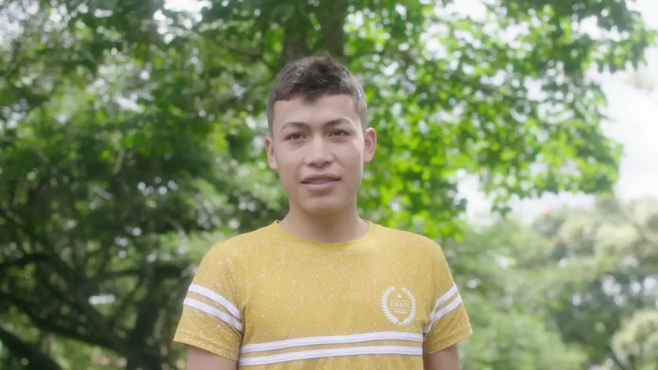 brunette man looks at the camera outdoors and smiles surrounded by trees exuding experience and confidence his smile telling stories of wisdom