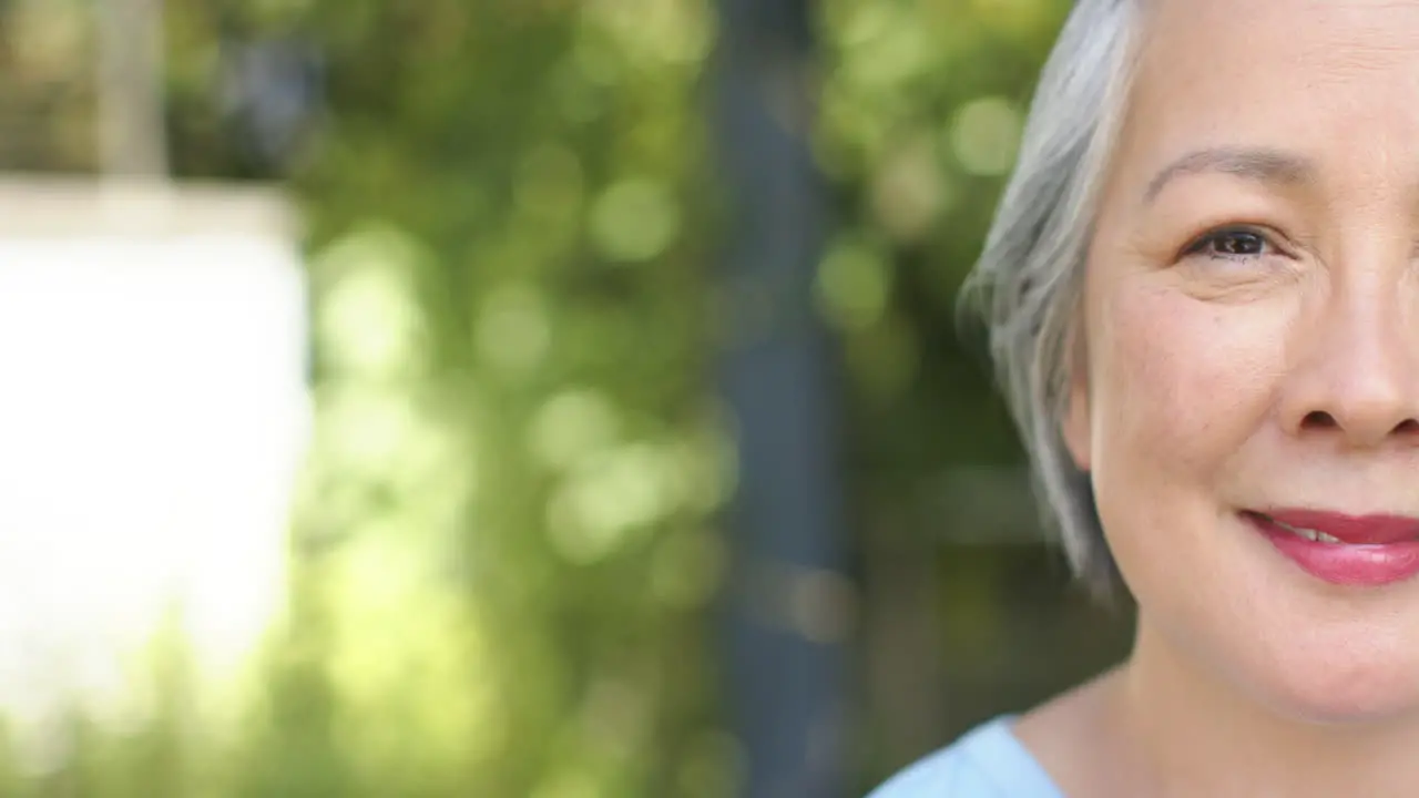 Close-up of a smiling senior Asian woman outdoors with copy space