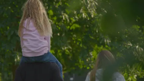 Long Shot of Young Girl Sitting On Her Father's Shoulders