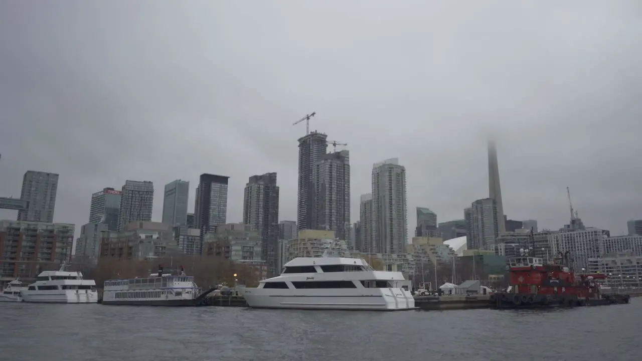 Cloudy day over Toronto's waterfront with moored boats and the CN Tower partly visible in mist