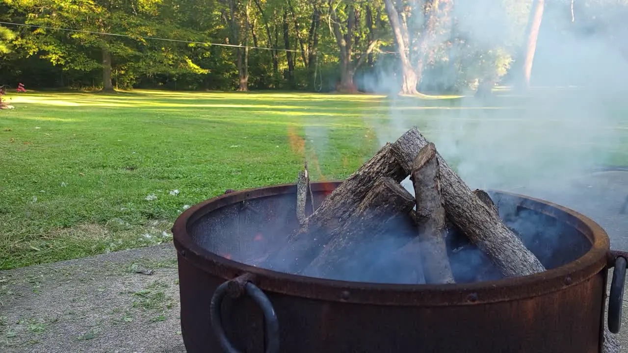 A side view of small campfire with gentle flames in the garden during a glowing sunshine