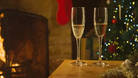 Sliding Close Up of Two Glasses of Champagne On Table In Front of Fireplace