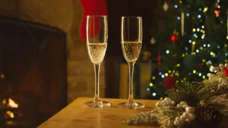 Close Up of Two Glasses of Champagne On Table In Front of Fireplace