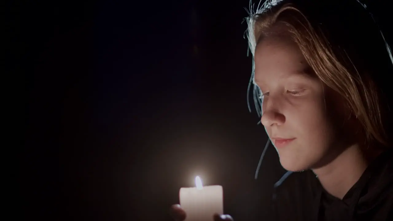 Side view child looking at a candle burning in the dark