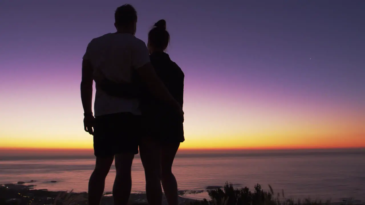 Couple standing and kissing on a beach by the sea at sunset