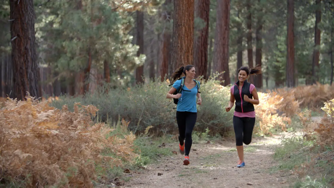 Two young women running in a forest