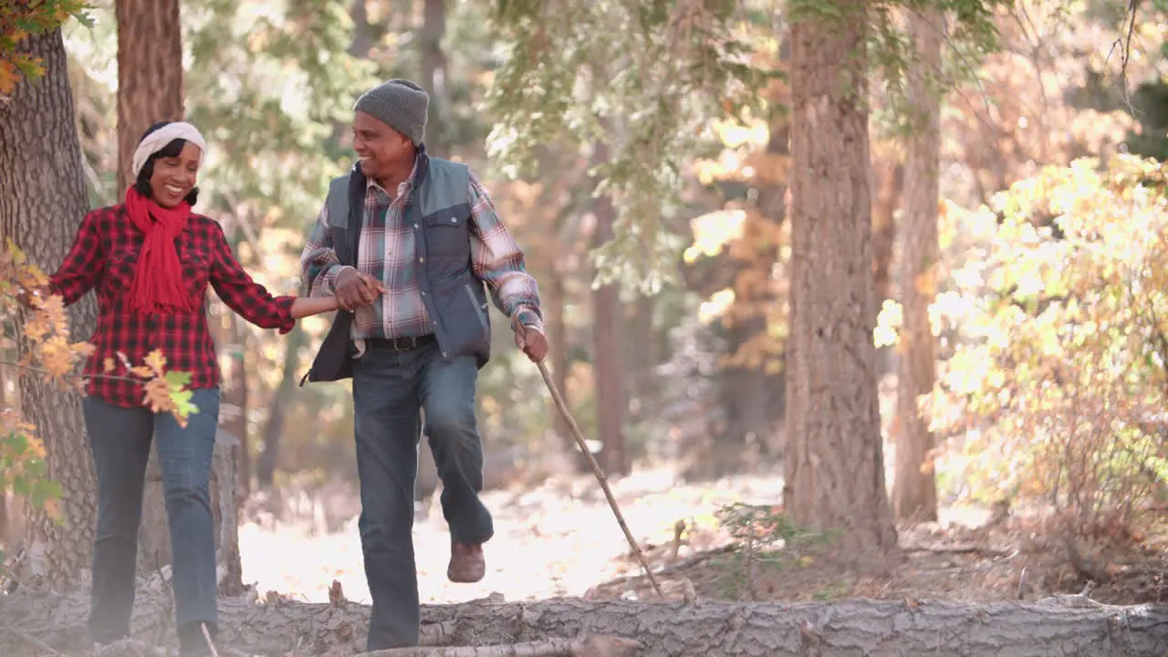 Senior couple in a forest walk to camera on left of frame