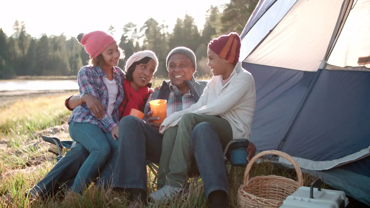 Grandparents and grandchildren relaxing outside tent by lake