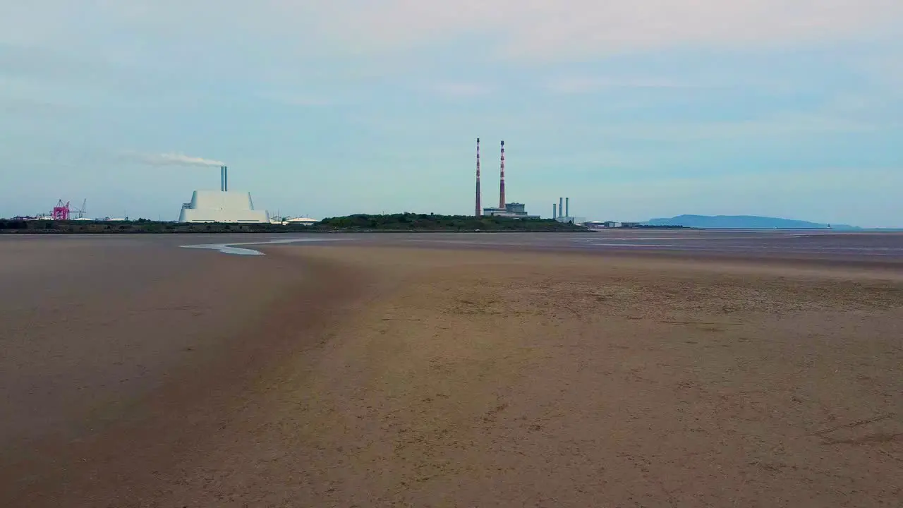 A low drone video of The empty beach at Sandymount strand with the Dublin city incinerator and Poolbeg chimneys