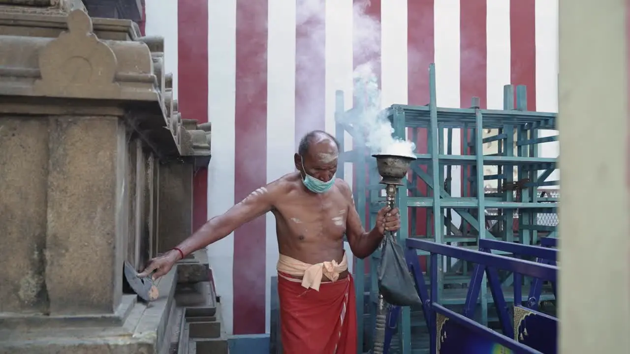 An old Hindu priest uses incense in a temple