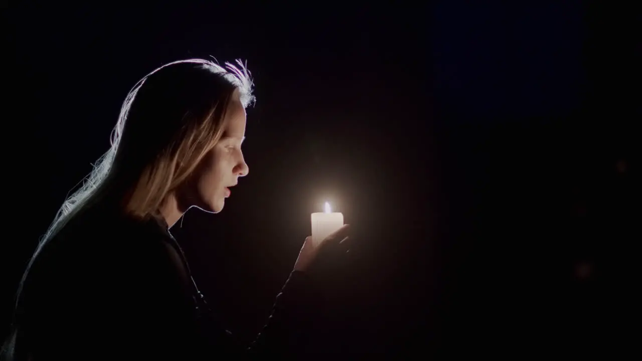 Portrait of a child looking at a candle burning in the dark Side view