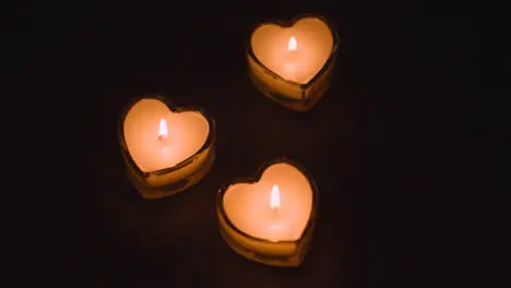 Close Up Of Three Romantic Lit Heart Shaped White Candles On Black Background With Copy Space 1