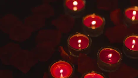 Romantic Lit Red Candles On Background Covered In Rose Petals