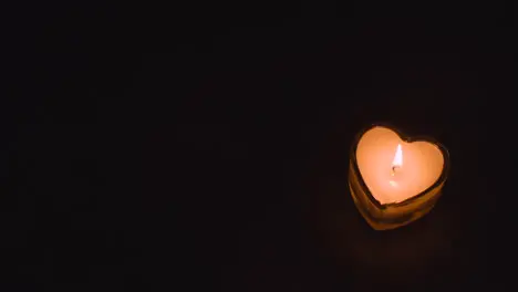 Close Up Of Romantic Lit Heart Shaped White Candles On Black Background With Copy Space