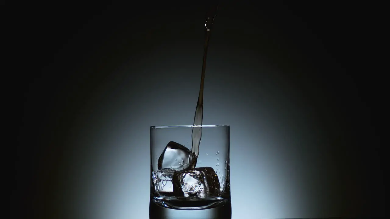 Close-Up of Liquor Pouring Over Ice Cubes in Glass