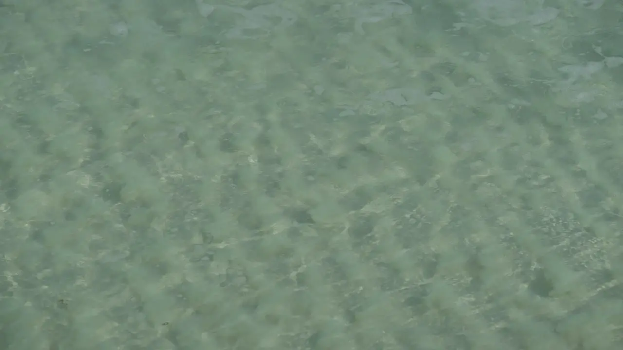 Super clear water wave rolling onto shore ripple pattern in sand