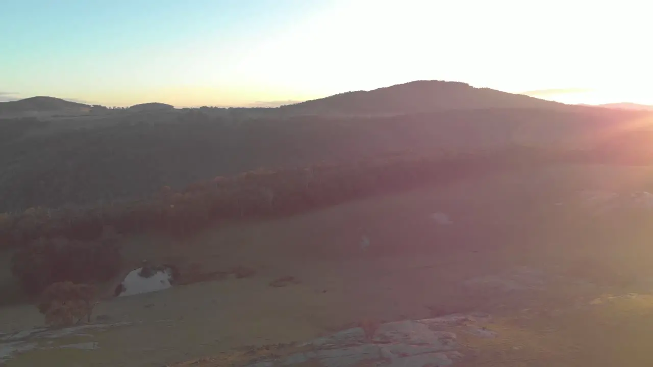 Aerial shot orbiting around big green fields in the strathbogie ranges with the early morning sun reflecting