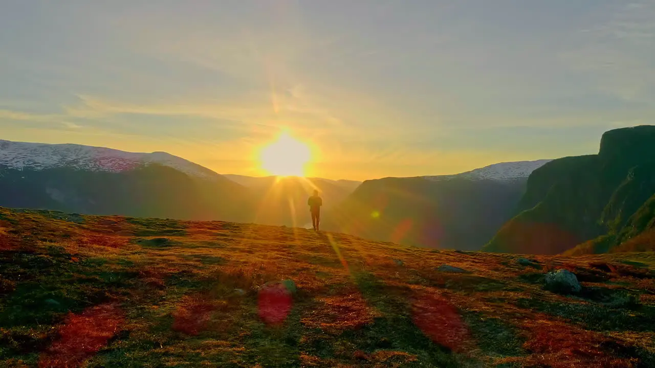 Mysterious man walking towards sun on the mountain top