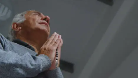 Low Angle Shot of Senior Man Praying with Rosary Beads