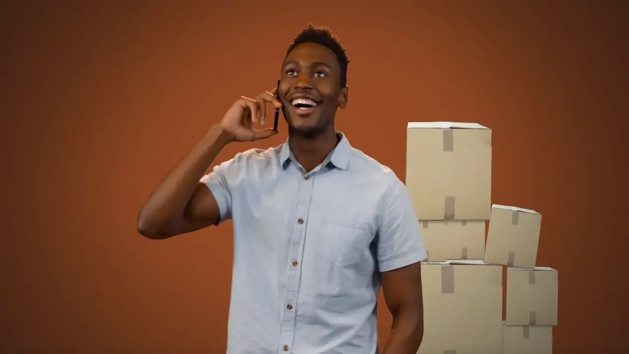 Animation of smiling man talking on smartphone with stacks of boxes on orange background