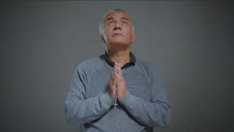 Portrait Shot of Senior Man Praying with some Rosary Beads