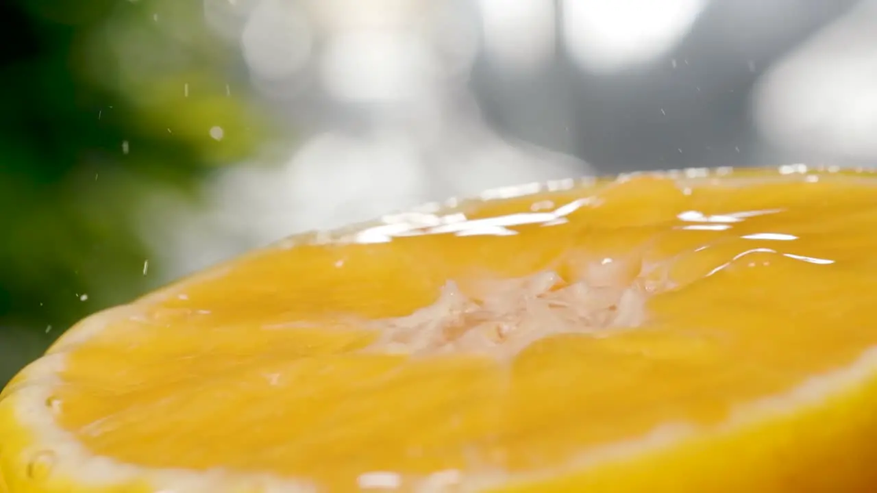 Extreme macro shot of Fresh water fall and splashing on half orange surface Slow motion