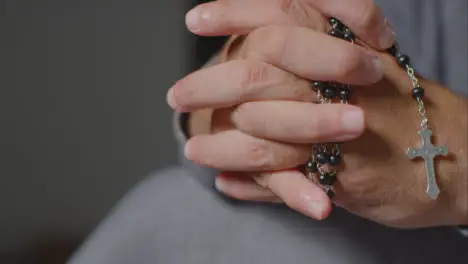 Sliding Shot of Senior Mans Hands Holding Rosary Beads