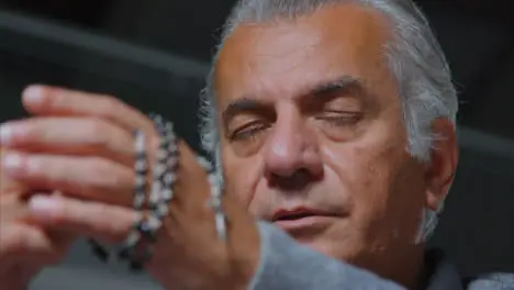 Low Angle Shot of a Senior Man Praying with Rosary Beads