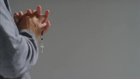 Close Up Shot of a Senior Mans Hands Holding Rosary Beads with Copy Space