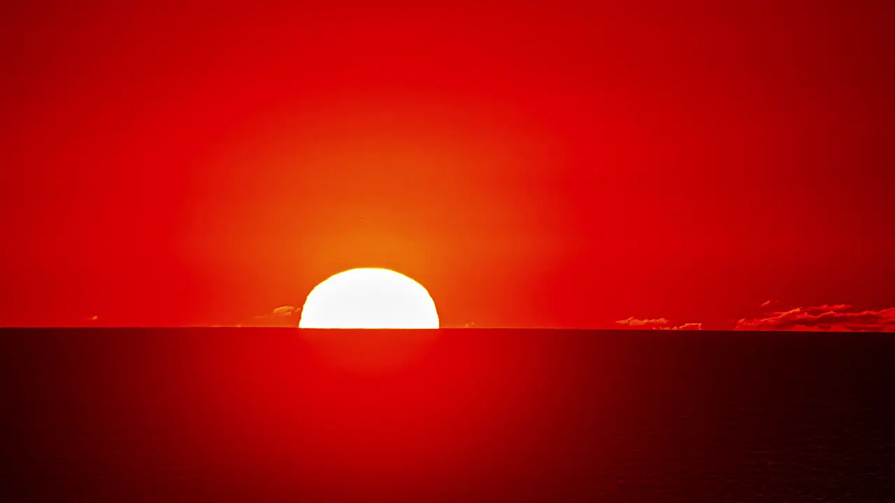 Time lapse of big glowing and yellow sun setting on red horizon