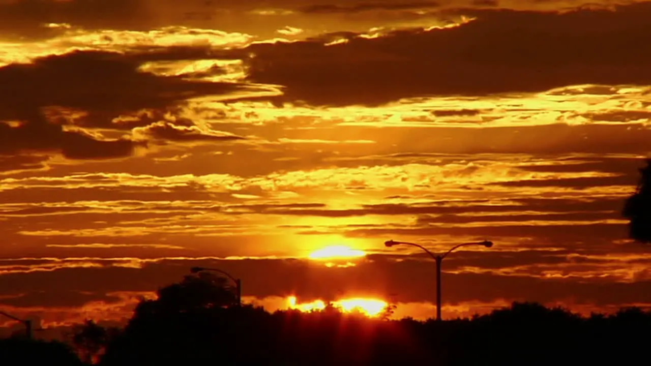 The sun glows behind clouds in a red and orange sky