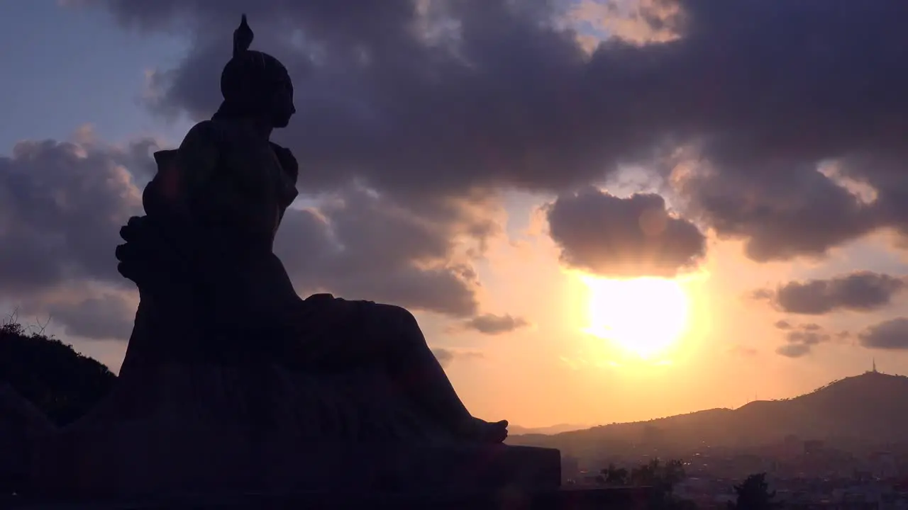 The sun sets behind a Roman statue in downtown Barcelona Spain