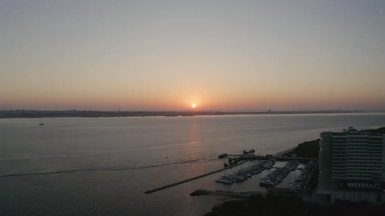 Wide view of sun rising behing sea and city in Portugal