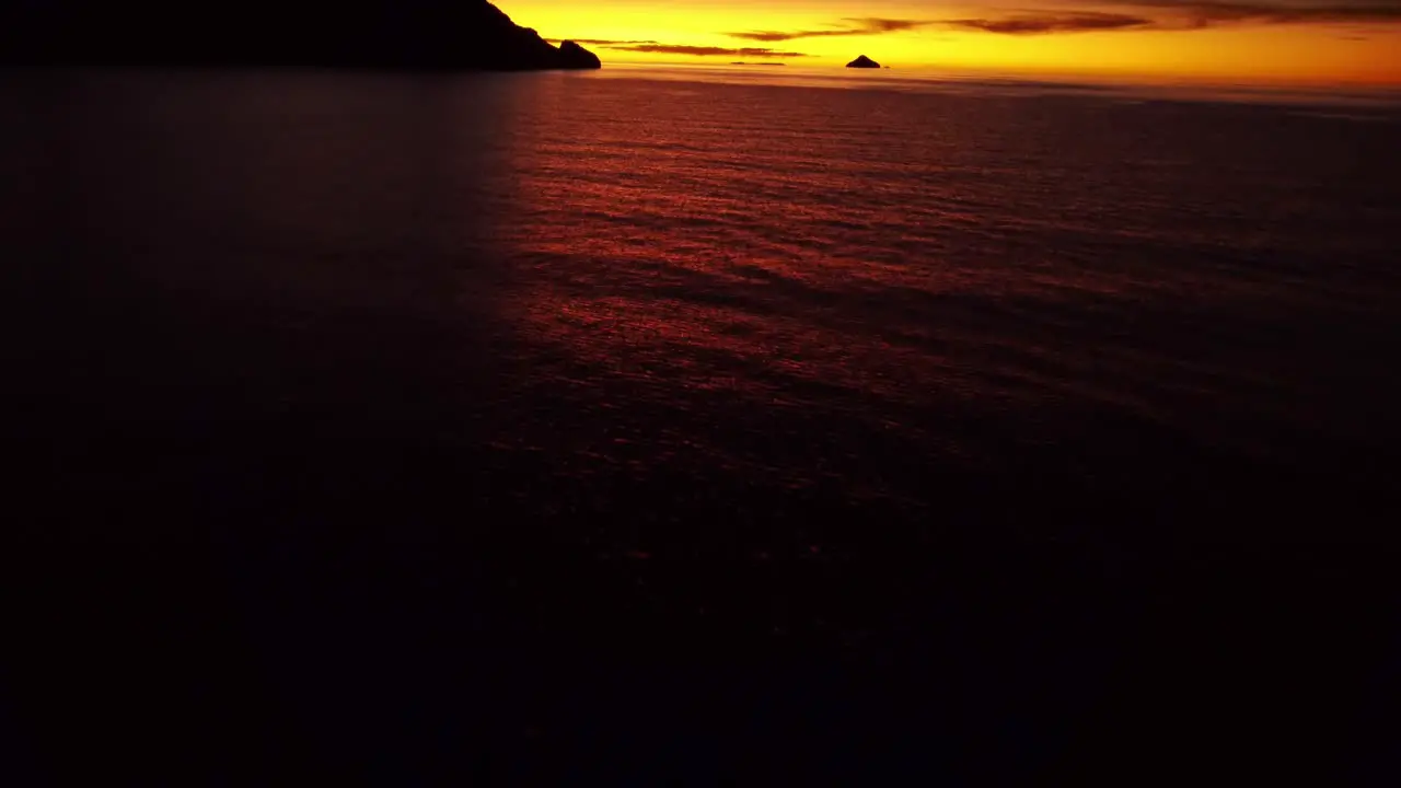 Aerial shot over the water revealing an orange sunset on Lake Titicaca in Peru