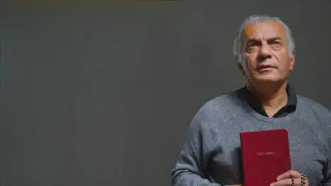 Portrait Shot of Senior Man Praying with Holy Bible with Copy Space