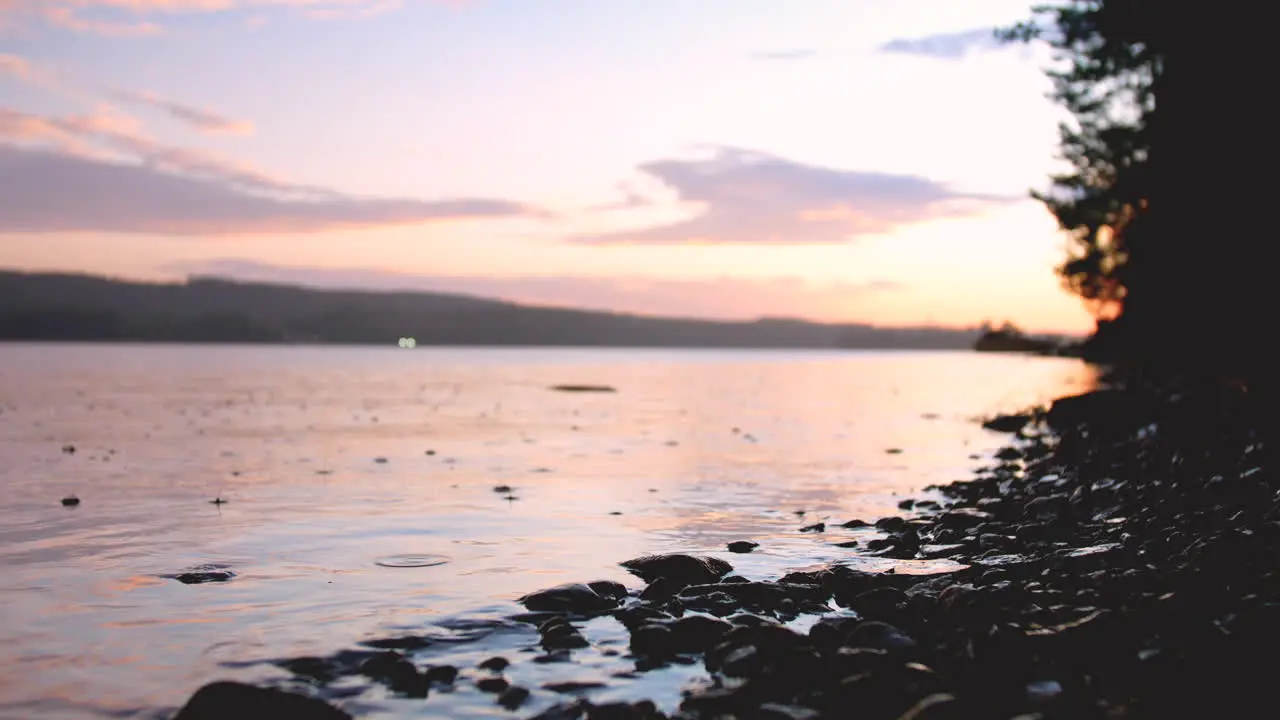 Close up at ground level of rain on the lake at sunset