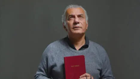 Portrait Shot of Senior Man Praying with Holy Bible