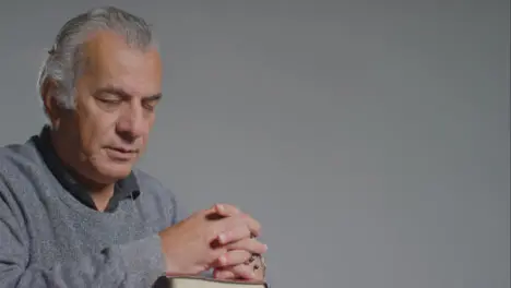 Portrait Shot of a Senior Man Praying with Rosary Beads