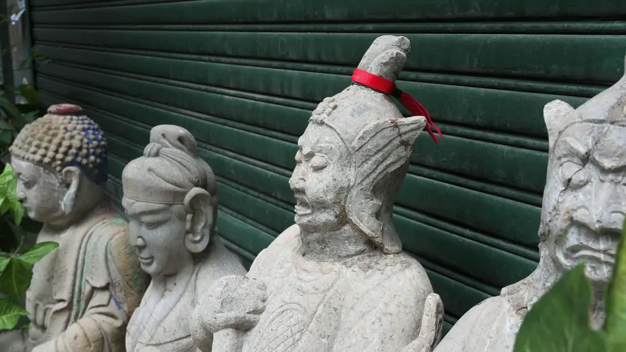 Religious Buddhist stone statues are seen in front o a closed antique shop