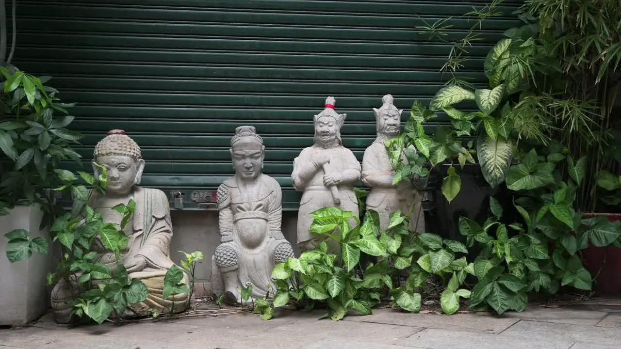 Religious Buddhist stone statues for sale guard the entrance of closed antique shop